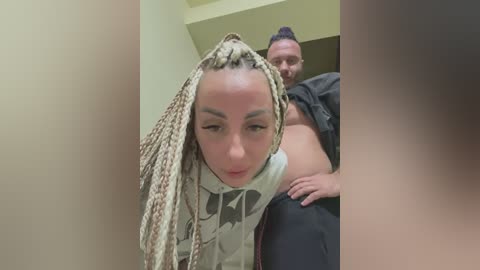 Media: A video captures a man holding a young woman with braided hair, both in a doorway, smiling. The background is a beige wall and green ceiling.