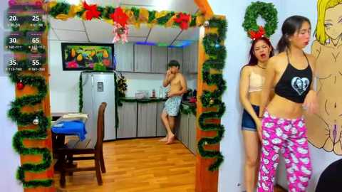 Media: A candid video captures a young man in a kitchen, shirtless, wearing pajama shorts, while two women in festive pajamas lean against a wall in the background.