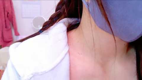 Media: A close-up video of a woman with light skin and long brown hair, wearing a blue bra, embracing a fluffy white pillow. The background shows a blurred pink towel and a round mirror.