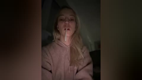 Media: A dimly lit video shows a blonde woman with her mouth open, drool dripping down, wearing a light-colored robe, in a shadowy, possibly bedroom setting.