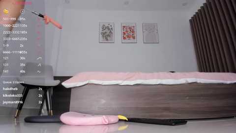 Media: A video of a modern bedroom with a wooden bed, pink and white sheets, three framed artworks on the wall, and a hand holding a smartphone.