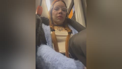 Media: A video of a young woman in an airplane seat, wearing a panda-themed costume with a white shirt, brown suspenders, and blue furry sleeves. She has glasses, auburn hair, and a serious expression.