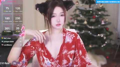 Media: Video of a young East Asian woman in a red kimono, with black cat ears, in front of a Christmas tree, with social media app interface overlay.