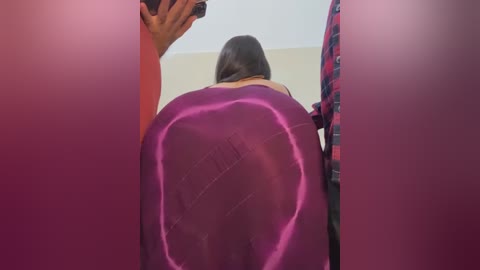 Media: Video of a woman with long brown hair in a pink, form-fitting dress, bending over in a bathroom, reflecting in a mirror.