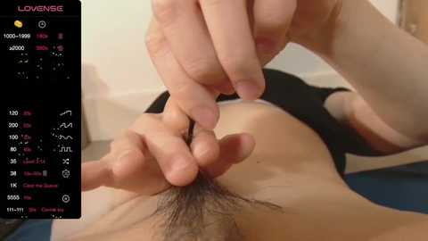 Media: Video of a close-up of a man's pubic hair being trimmed by another person's fingers. Background shows a smartphone screen displaying the \"LoveSense\" app.