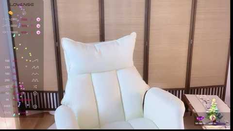 Media: Video of a white, modern, cushioned armchair with a soft, plush texture in a minimalist room with beige, sliding shoji screens and a small side table.