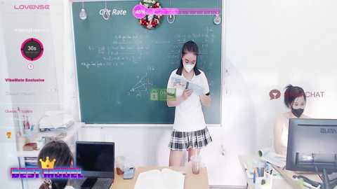 Media: Video of a VR scene featuring an Asian woman in a white mask, black plaid skirt, and glasses, teaching a class in a cluttered room with a chalkboard.