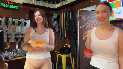 Media: Video of a smiling woman with long brown hair, wearing a white tank top and no pants, holding a slice of watermelon, in a cozy bar with wooden decor, beer signs, and colorful wall art.