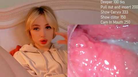 Media: A blonde woman in a beige hoodie, with a light complexion, lies on a bed, looking at a smartphone. A close-up of a pink, moist oral cavity is shown.