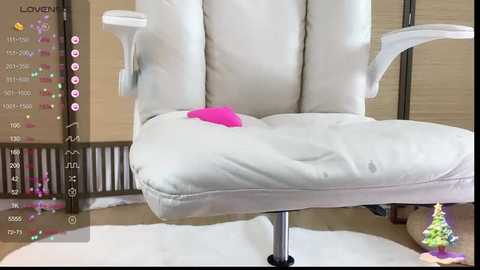 Media: Video of a white leather office chair with a pink pillow on its seat, placed on a circular white rug, against a beige wall, with a digital overlay showing \"LOVE\" in pink.