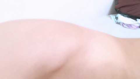 Media: A video of a close-up, light-skinned female buttock, with a hint of a hand resting near the edge of a bathtub. The background is a white, clean surface.