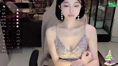 Media: Video of an Asian woman with fair skin, wearing a sequined purple dress, sitting in an office chair, background includes a desk with a computer and a tree ornament.