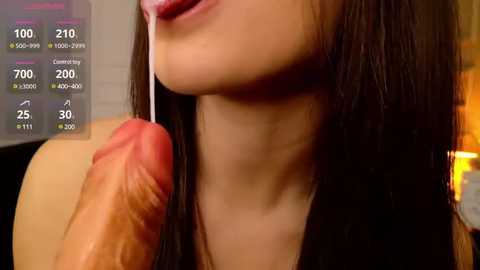 Media: Video of a young woman with long dark hair, smiling with a large, erect penis in her mouth, surrounded by a digital interface displaying sexual stats.