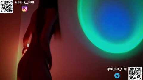 Media: Video of a woman's silhouette with long hair, standing in a dimly lit room with a green and blue light ring on the wall. QR codes and social media icons are visible in the top left corner.