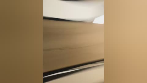 Video of a beige wall with slight texture, featuring a blurred vertical black line running down the center, suggesting a slight distortion or motion blur.