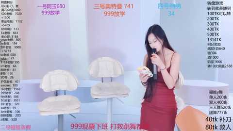 Media: Video of an Asian woman with long black hair, wearing a red dress, eating a burger in a minimalist, modern interior with white furniture.