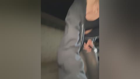 Media: A blurred video captures a person in a gray sweater, likely female, walking through a dimly lit room with beige walls and dark furniture.