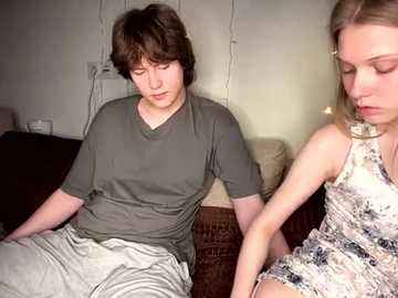 Media: Video of a young boy and girl in casual attire on a couch; the girl wears a floral dress, the boy a gray t-shirt and beige shorts.