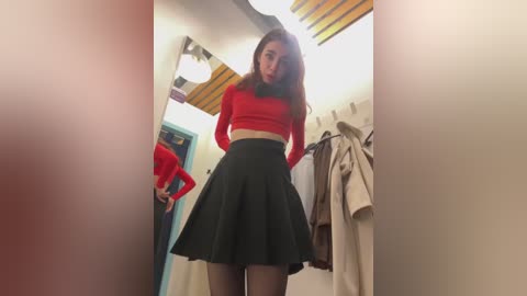 Media: A video of a young woman with long, straight brown hair, wearing a red long-sleeve top and high-waisted black skirt, standing in a brightly lit, modern room with wooden ceiling beams and hanging coats.