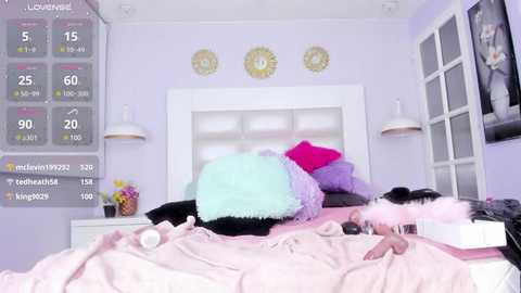 Media: Video of a pastel-colored bedroom with a white headboard, pink blanket, and a mix of colorful pillows. A digital clock display and framed sunburst art adorn the walls.