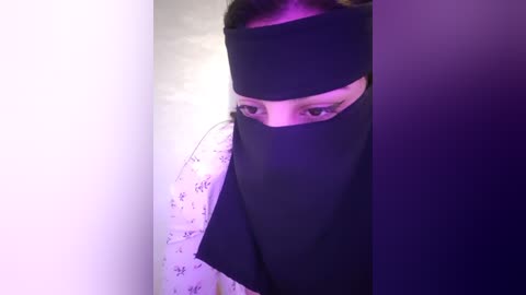 Media: Video of a person wearing a black mask and white robe with Japanese kanji characters, standing in a dimly lit room with purple and white lighting.