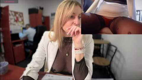 Media: Video of a blonde woman in a white lab coat and black top, sitting at a desk in a cluttered office. Inset: close-up of a woman's buttocks with a visible anal bead. Background shows a messy room with computer monitors.