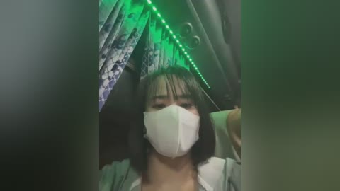 Media: A video of an Asian woman with a mask, standing in a dimly lit room with green LED lights, wearing a patterned umbrella.