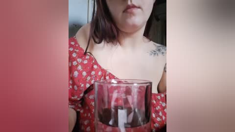 Media: A video of a fair-skinned woman with shoulder-length dark hair wearing a red floral dress, holding a glass of wine, with a visible tattoo on her right shoulder.