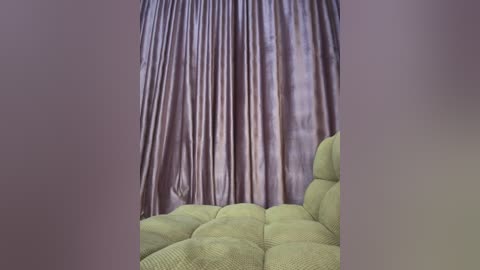 Media: A video of a light green, textured fabric couch with a pleated, soft pink curtain backdrop, creating a serene and cozy atmosphere.