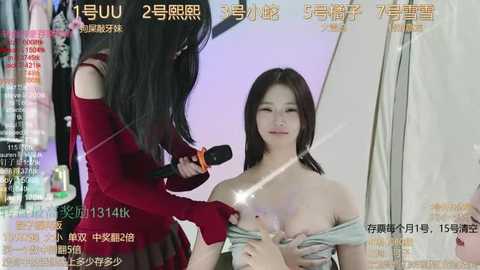 Media: Video of a young Asian woman with long black hair, partially undressed, being interviewed on a talk show. She wears a red off-shoulder top and holds a microphone.