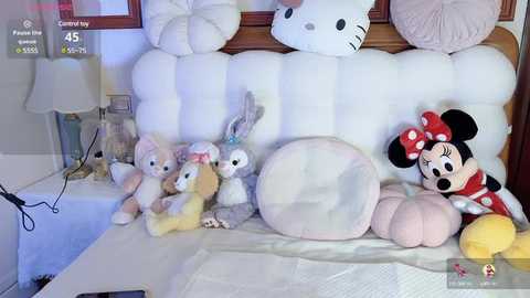 Media: Video of a plush bed featuring plush toys including Minnie Mouse, bunny, and bear, in a cozy, well-lit bedroom with white and pink bedding.