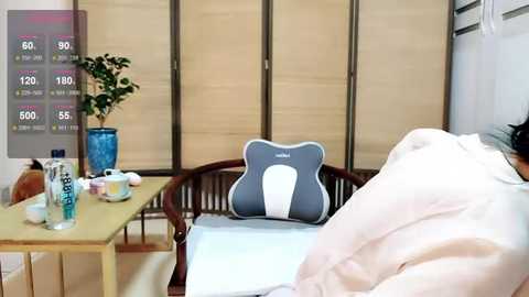 Media: Video of a hospital room with a patient in a white robe, a blue water bottle, and a gray pillow with a white bear on a light wooden table.