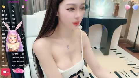 Media: Video of a pale-skinned, petite Asian woman with long, straight black hair, wearing a low-cut white lace camisole. She has a small chest, a slender physique, and sits in a modern room with a piano and bookshelf in the background.