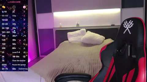 Media: A video of a modern bedroom with a white bed, black and red gaming chair, and a nightstand. The background features a digital clock displaying a countdown timer. The room is illuminated with purple and white lights.