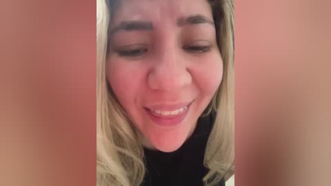 Media: Video of a young woman with light skin, blonde hair, and fair eyebrows. She has a closed-mouth smile, and her eyes are partially closed. The background is a soft pink.