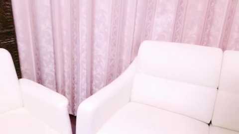 Media: A video of a minimalist living room with white leather armchairs facing a soft pink, floral-patterned curtain in the background. The room has a clean, modern aesthetic.