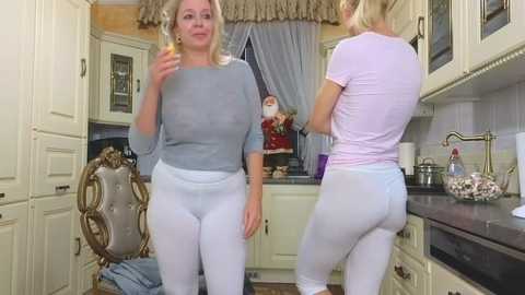 Media: Video of two middle-aged women in a kitchen; one in a grey sweater and white pants, the other in a pink top and white pants.