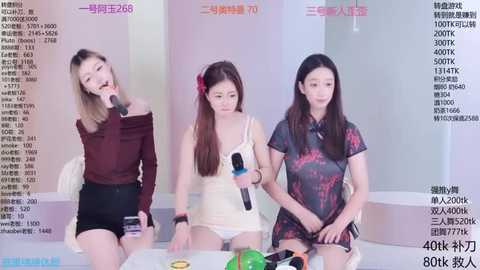 Media: Video of three Asian women, one with a red bow, wearing casual outfits, sitting at a table, holding microphones, in a modern indoor setting with Chinese text.