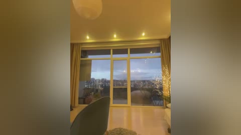 Video of a modern living room with large floor-to-ceiling windows showcasing a cityscape at dusk, beige walls, recessed lighting, and a plush carpet.