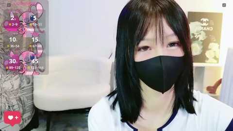 Media: Video of an Asian woman with straight black hair, wearing a black face mask and white t-shirt, indoors, featuring a My Little Pony sticker on the left.