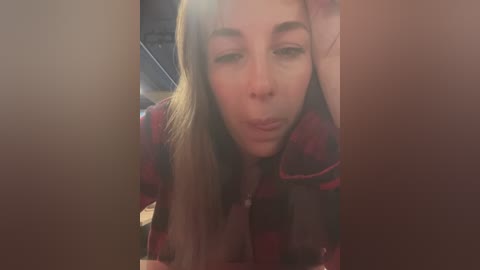 Media: A video of a young woman with long, light brown hair, wearing a red and black plaid shirt, making a kissy face through a narrow gap between two wooden doors.