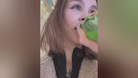 Media: A video of a young Caucasian woman with light skin and shoulder-length brown hair, wearing a black top, playfully biting her finger in a close-up shot.