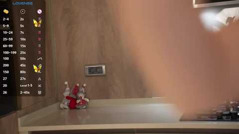 Media: Video of a modern kitchen with a beige countertop, featuring a decorative white and gray reindeer figurine and a digital clock on a light brown wall.