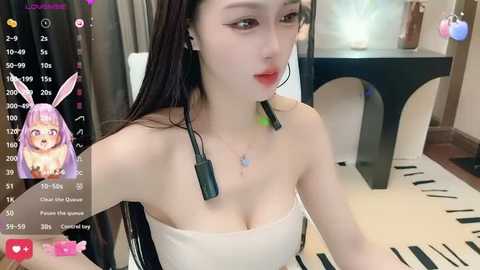 Media: A video of a young, fair-skinned woman with long, straight, dark hair and pink bunny ears, wearing a strapless white top and black headphones. The background features a modern room with a black table and a white lamp.