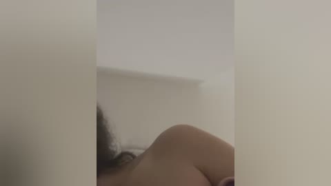 Media: A video of a nude woman with long, dark hair lying on a bed, partially obscured by a white sheet, in a dimly lit room.