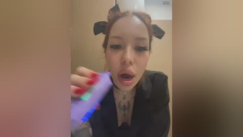 Media: A video of a pale-skinned woman with a black headband, red nails, and black clothing, brushing her teeth in a beige-tiled bathroom.