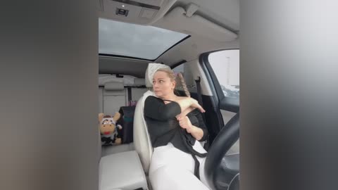 Media: A candid video shows a woman in a black top and white pants buckling her seatbelt in a car. The interior is light with a stuffed animal in the background.