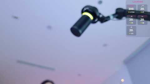 Video of a blurred, black microphone suspended from a white ceiling, with a digital display showing \"300\" and \"20\" on the right side.