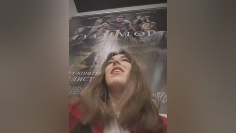 Media: Video of a young woman with long brown hair, smiling, standing in front of a poster for the Russian film \"\u0410\u043b\u044c\u0444\u0430\" (Alpha). The poster features a group of soldiers in uniform.