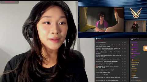 Media: Video of an Asian woman with long black hair, wearing a black shirt, against a plain background. A TV screen in the background shows a woman in a purple top and a man in a beige shirt.